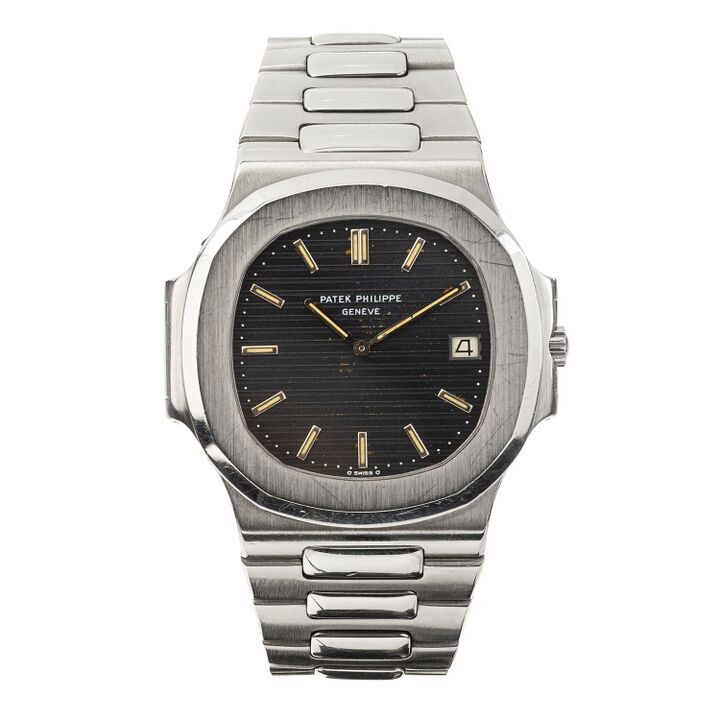 A Nautilus has a broad rounded bezel, side projections and a striped dark dial on a metal bracelet.