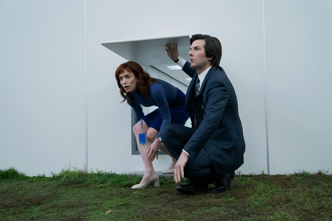 Mark crouches beside Helly, with a white-dial watch visible below his jacket cuff.