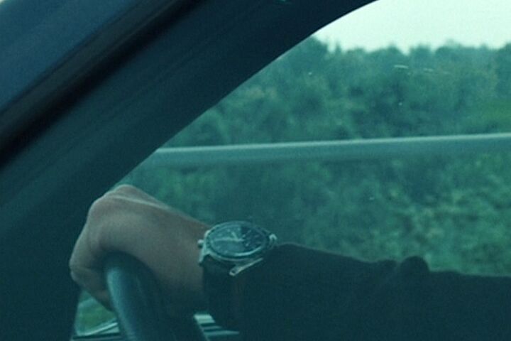 George Clooney wearing an Omega Speedmaster Professional on leather in The American
