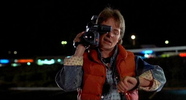 Michael J. Fox as Marty McFly filming with a camcorder and checking his watch in Back to the Future