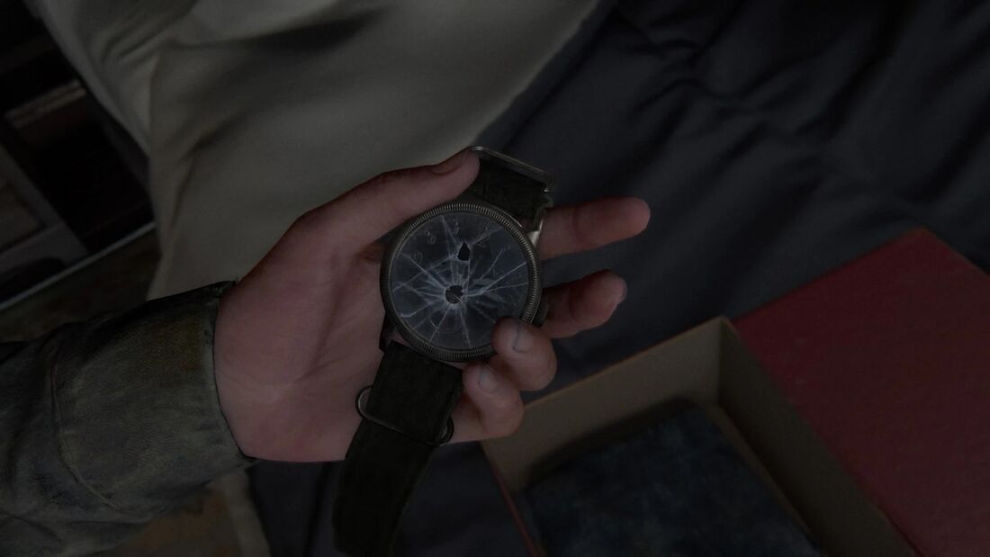 A hand holds an olive-strapped watch with large numerals and a shattered crystal.