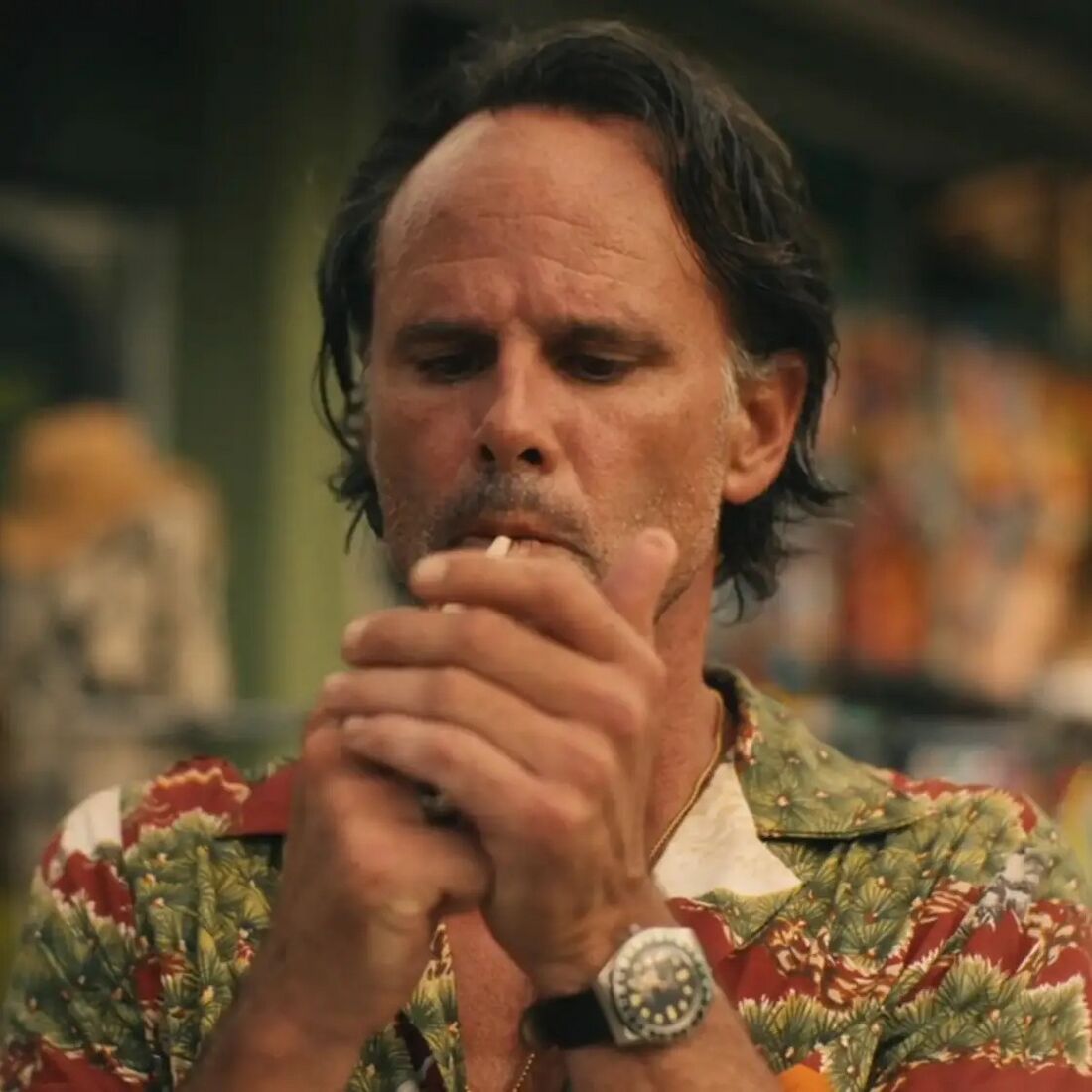 Rick lights a cigarette with a round watch on a black strap exposed at his left wrist.